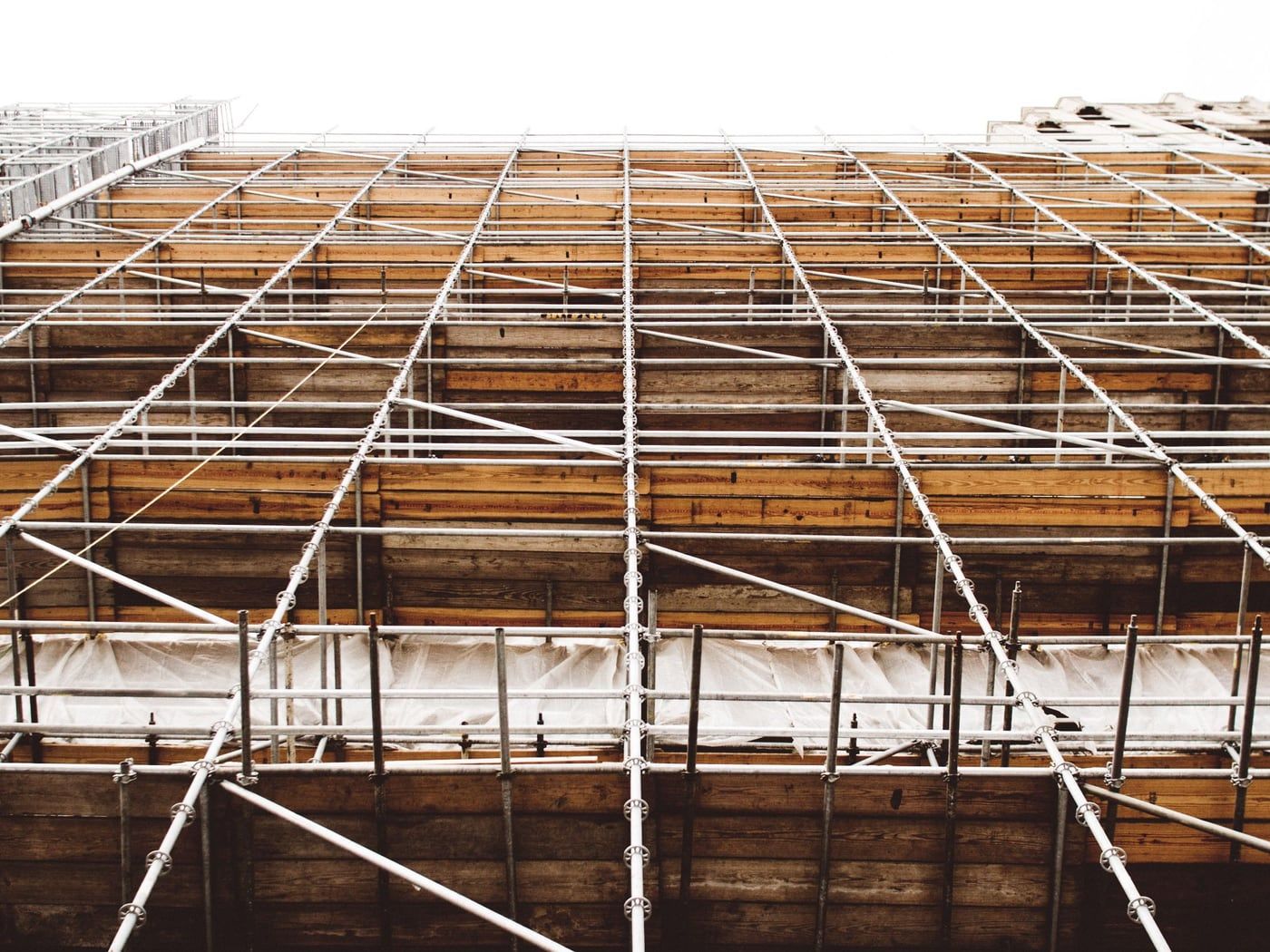 Gerüstlagen mit Holzbelägen vor der Fassade. Dämmung und Anschlüsse sind hier noch zugänglich.
